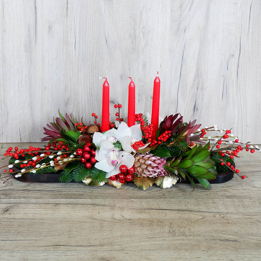 Χριστουγεννιάτικη σύνθεση με κεριά, ίλεξ, ορχιδέες, ανανά και χριστουγεννιάτικη διακόσμιση .